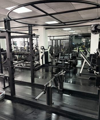 Instalaciones amplias y profesionales con racks de sentadillas, mancuernas y espejos de cuerpo completo.